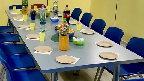 Stół w salce urodzinowej nakryty talerzykami, kubeczkami i napojami